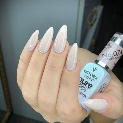 Unhas longas com verniz nude brilhante segurando frasco de esmalte Victoria Vynn.