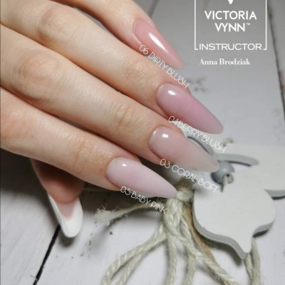 Unhas artificiais rosas translúcidas com etiquetas dos nomes dos tons em fundo branco com decoração de cordas e objeto branco