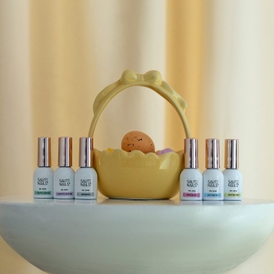 Frascos de verniz de unhas SAUTE NAILS em frente a cesto amarelo com ovos decorativos