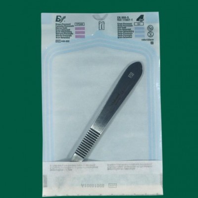 Pinça metálica esterilizada em embalagem transparente sobre fundo verde