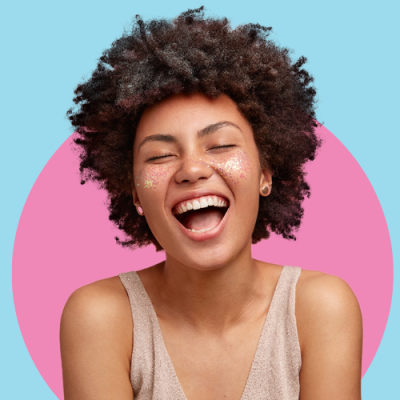 Pessoa sorridente com cabelo afro e blusa bege com fundo colorido