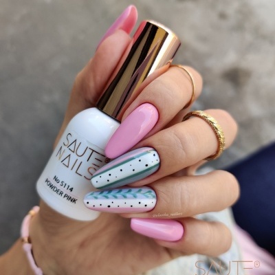 Unhas com verniz rosa e padrão decorativo segurando frasco de verniz SALUTE NAILS branco e dourado