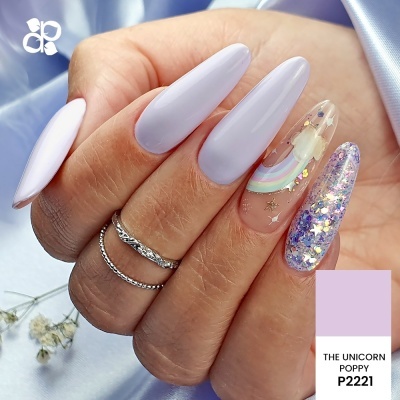 Unhas postiços lilás, rosa claro e transparentes com glitter, estrelas e arco-íris, com dois anéis prateados, fundo lilás e flores secas