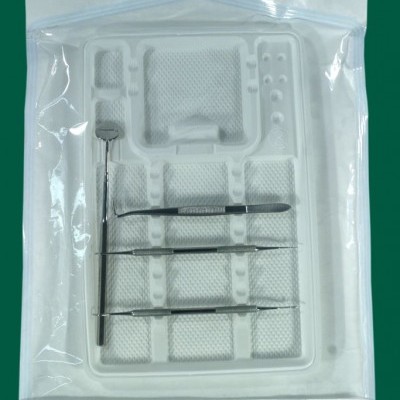 Conjunto de instrumentos médicos em bandeja branca dentro de embalagem de plástico transparente