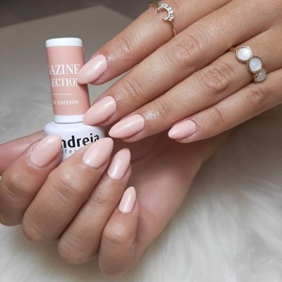 Mão com unhas pintadas de rosa claro segura frasco de verniz Andreia