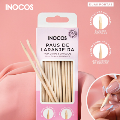 Caixa de pauzinhos de laranjeira INOCOS em fundo rosa com mãos e unhas visíveis