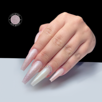 Unhas artificiais compridas com glitter rosa e uma unha branca perolada com cristais