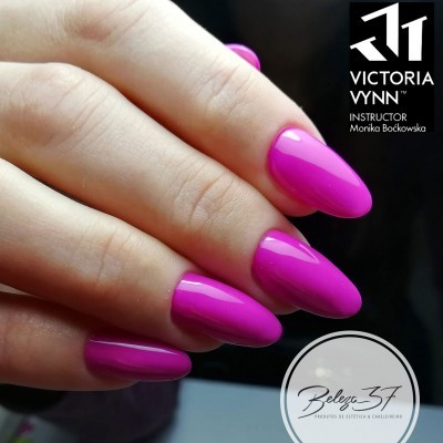 Mão com unhas rosa vibrantes e brilhantes em fundo escuro com logotipos visíveis