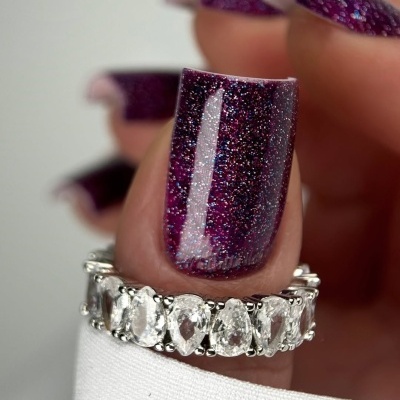 Anel com pedras transparentes e unhas roxas com glitter.