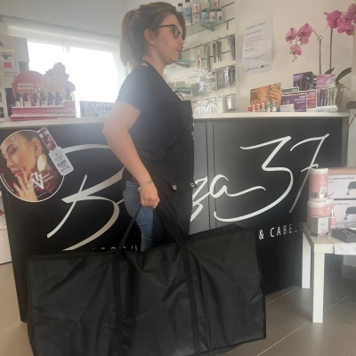 Mulher com bolsa preta gigante em balcão com texto Beleza 31 e flores cor de rosa