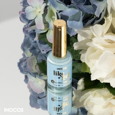 Frasco de verniz gel azul claro INOCOS com tampa dourada junto a flores