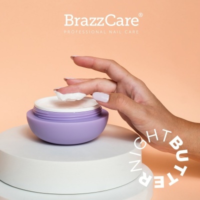 Mão feminina a pegar creme de um pote lilás sobre base branca, fundo laranja, textos BrazzCare e NIGHT BUTTER