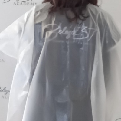 Pessoa vista de costas com plástico transparente sobre roupa preta com texto Belega 37 ACADEMY