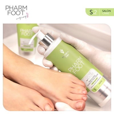 Frasco de creme verde e branco PHARM FOOT segurado por mão com luva branca junto a pés descalços femininos