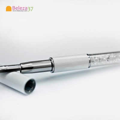 Caneta branca com cristais transparentes e tampa ao lado sobre fundo branco