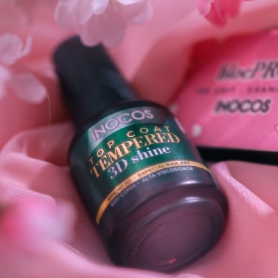 Frasco de verniz de unhas JNOCOS Top Coat Tempered 3D Shine sobre tecido rosa