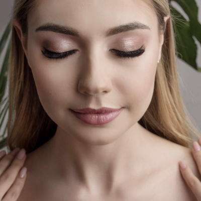 Mulher com maquilhagem subtil e cabelo loiro com plantas ao fundo