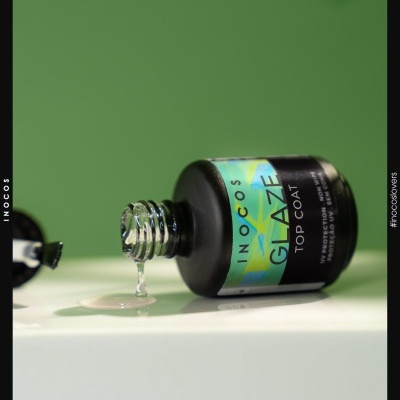 Frasco preto de vidro com rótulo colorido e líquido transparente saindo da tampa aberta