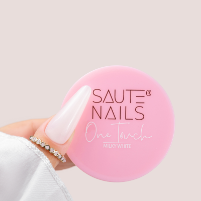 Contém um frasco rosa de produto para unhas SAUTE NAILS e mão com unha longa branca