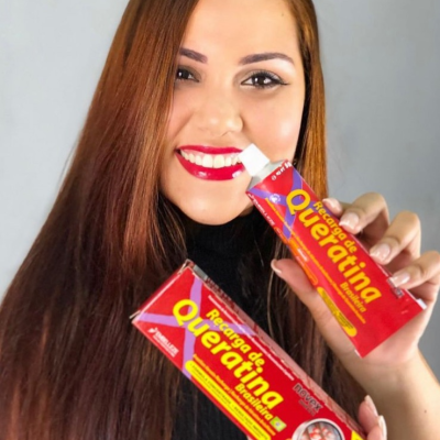 Mulher segurando embalagens vermelhas de Recarga de Queratina Natural