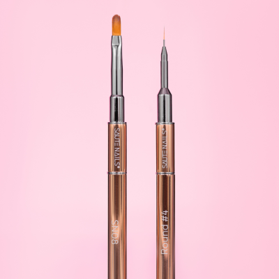 Dois pincéis de unhas metálicos castanho-alaranjados em fundo rosa com texto SAUTE NAILS