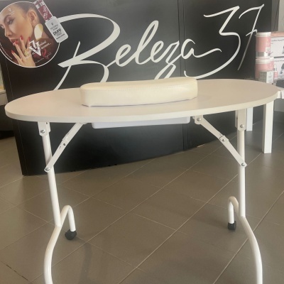 Mesa de estética oval branca com apoio almofadado num salão com painel preto 'Beleza 37'