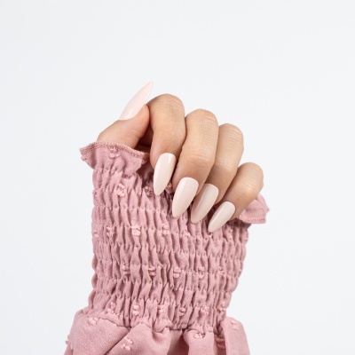 Mão feminina com unhas postiças cor de rosa claro e manga rosa texturizada
