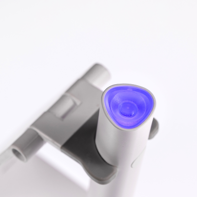 Dispositivo eletrônico branco com luz azul triangular e texto SAUTE NAILS