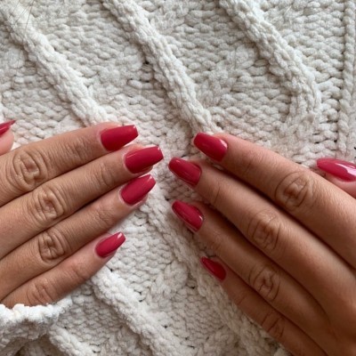 Mãos com unhas vermelhas sobre tecido branco texturizado