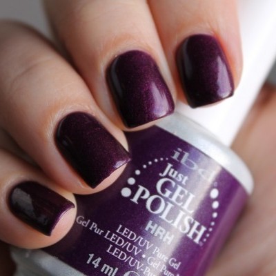 Unhas com verniz gel roxo escuro, brilho, segurando frasco de verniz gel HRH