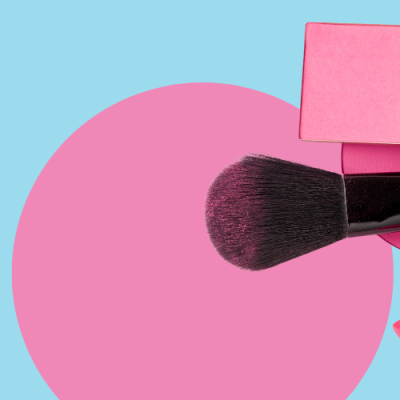 Produtos de maquilhagem rosa e lilás sobre fundo azul com círculos cor-de-rosa