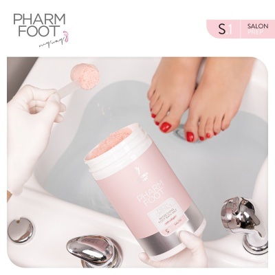 Pés femininos com verniz vermelho em banho de pés e recipiente rosa PHARM FOOT SALON PREP S1 com pó granuloso