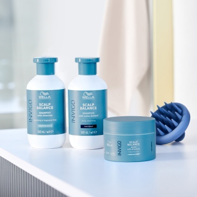 Produtos Wella INVIGO SCALP BALANCE sobre superfície branca com acessório de massagem azul.