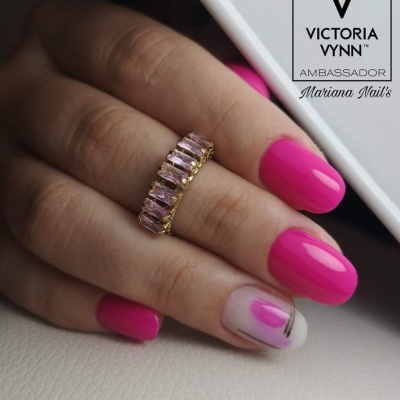 Mão com unhas cor de rosa vibrante e anel dourado com pedras rosa
