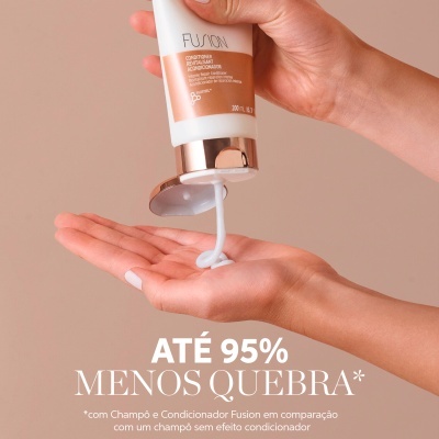 Pessoa a espremer creme branco de embalagem Fusion branca e dourada contra fundo rosa