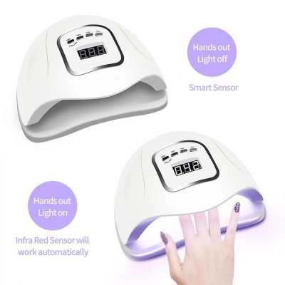 Secador de unhas branco com visor digital e mão de pessoa usando aparelho com luz UV acesa