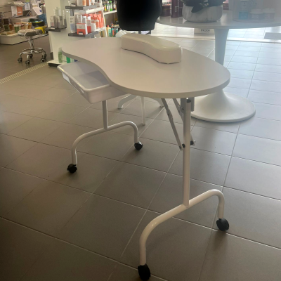 Mesa branca de manicure com apoio acolchoado em loja de cosméticos