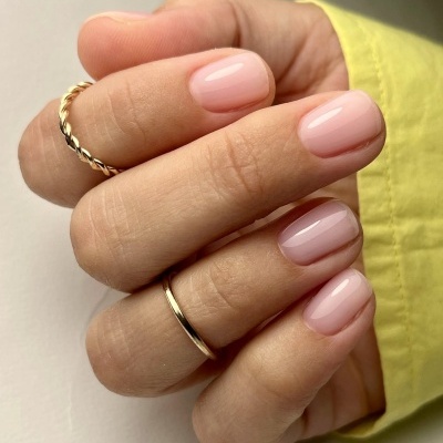 Mão com unhas cor de rosa claro e argolas douradas
