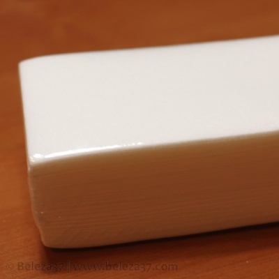 Bloco de borracha branca retangular com cantos arredondados sobre superfície de madeira