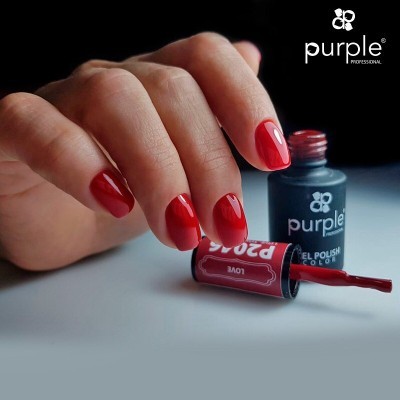 Mão com unhas vermelhas brilhantes ao lado de frasco aberto de verniz 'purple'