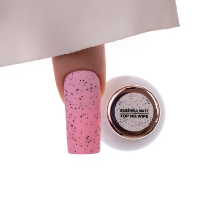 Unha postiça rosa fosca com manchas pretas e frasco branco com tampa dourada e texto EGGSHELL MATT TOP NO WIPE.
