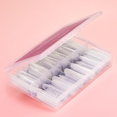 Estojo transparente com tubos plásticos pequenos organizados em divisórias sobre fundo rosa