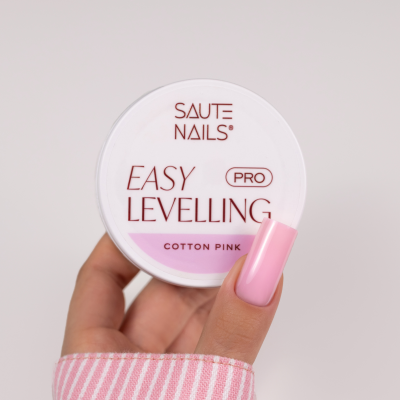 Frasco de produto para unhas SAUTE NAILS EASY LEVELLING PRO COTTON PINK com mão feminina e unha rosa