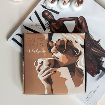 Caixa de verniz para unhas SAUTE NAILS Mocha Essence com ilustração de mulher e frascos de verniz sobre revista de moda com modelo.