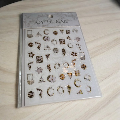 Adesivos metálicos dourados para unhas com padrões geométricos e florais em embalagem transparente