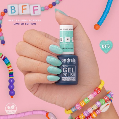 Mão segurando verniz de gel azul claro Andreia Professional BFF sobre fundo rosa com pulseiras coloridas