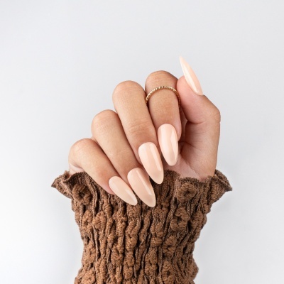 Mão com unhas compridas e cor creme e manga de malha castanha