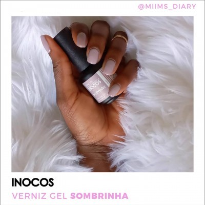 Verniz gel Inocos Sombrinha em mão com unhas pintadas sobre fundo branco felpudo