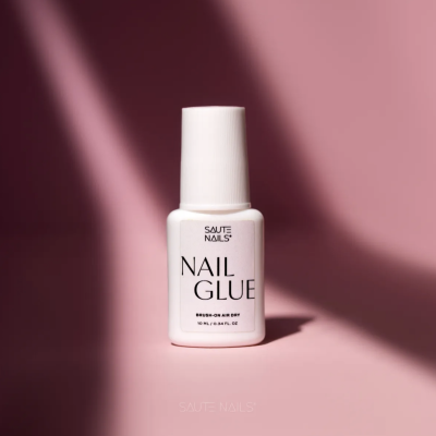 Frasco branco de cola para unhas com rótulo preto sobre fundo rosa