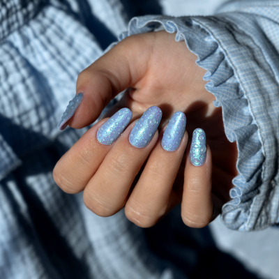 Unhas pintadas de azul com gotas de relevo e camisa azul-claro com rufos na manga